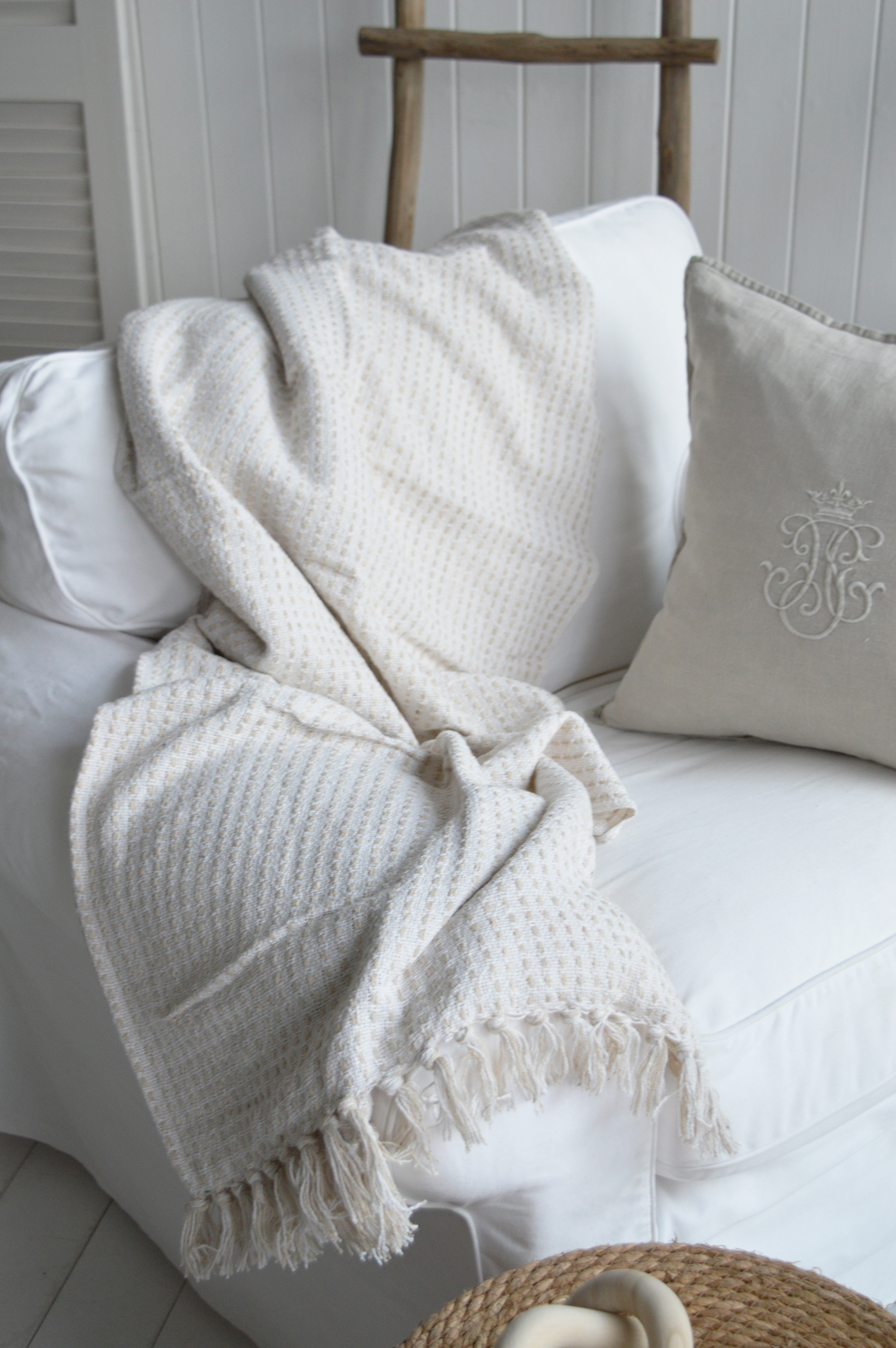 The soft texture of a white throw contrasts beautifully with natural elements like jute rugs, wicker furniture, and shiplap walls in Hamptons-style homes.