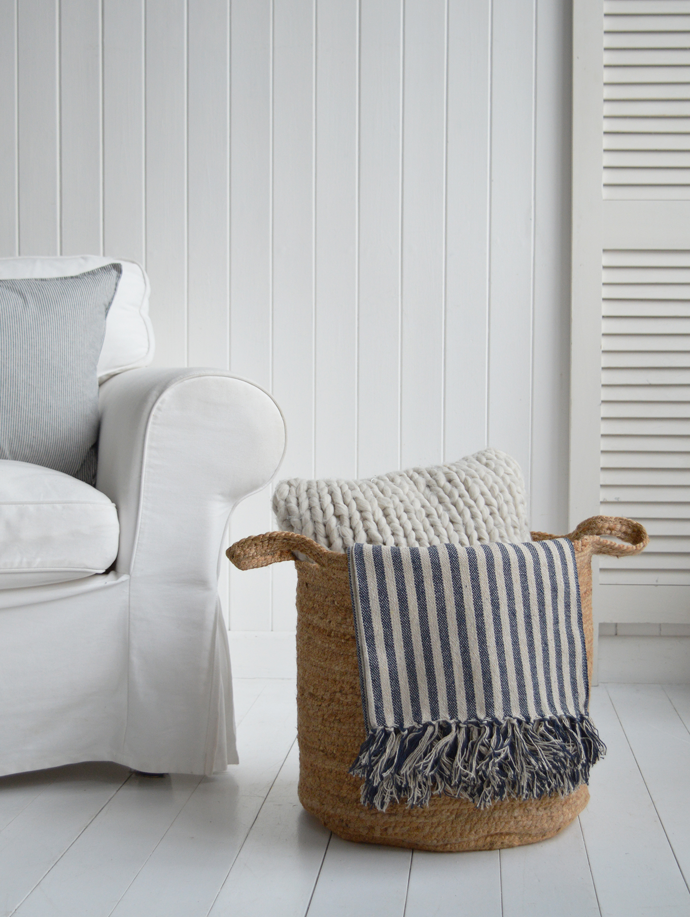 The Fall River basket, a large Seagrass basket beside a sofa, styled with Mapleton throw and Mayfair cushion for a Hamptons Beach House styled home interior