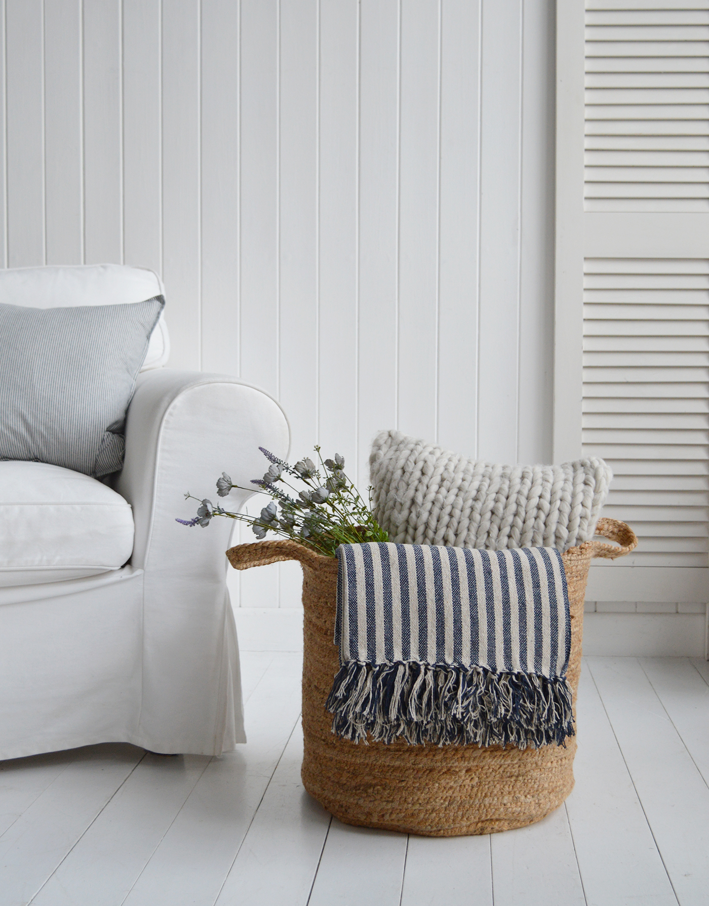 The Fall River basket, a perfect height basket beside a sofa, styled with Mapleton throw, Mayfair cushion and wild blue roses