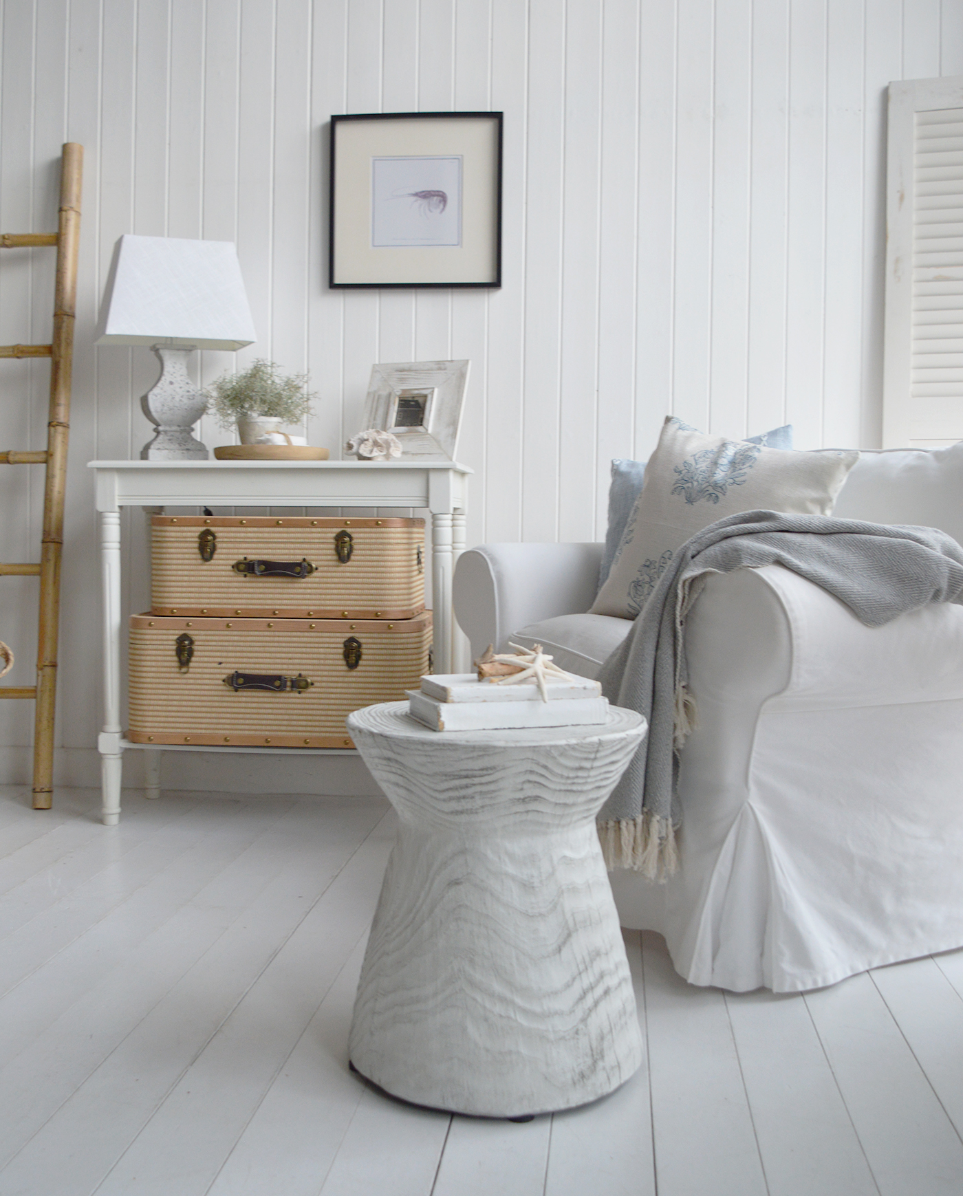 The look blends driftwood tones, linen fabrics, and wicker furniture to achieve a warm yet airy coastal feel.