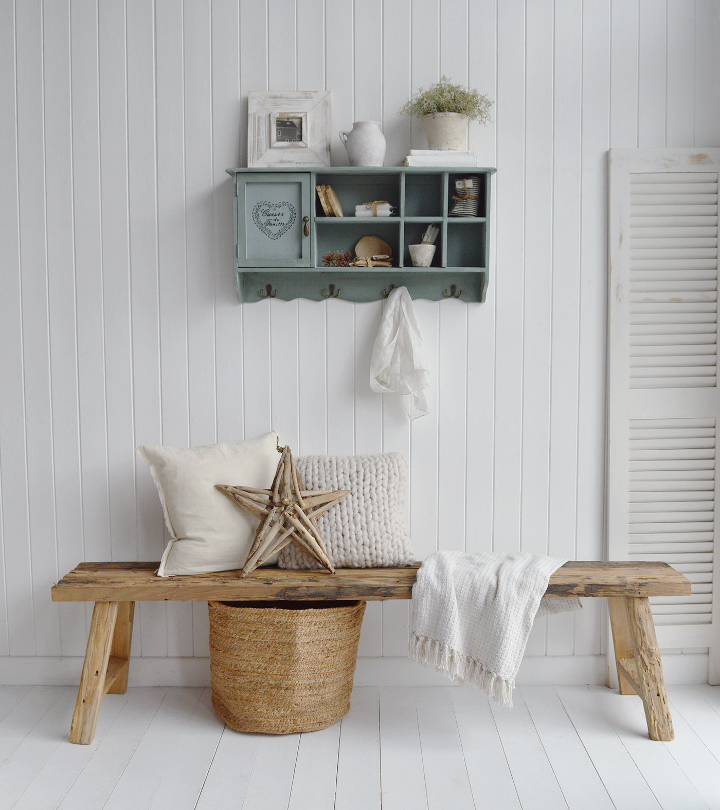 The rustic woodn bench layered with nuetral cushions and throws with baskets underneath for storage