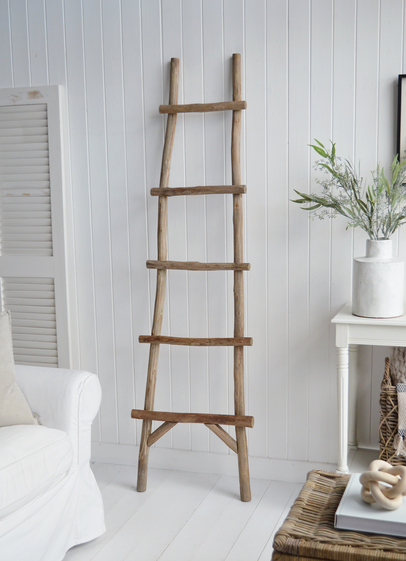  In the living room, this stylish ladder serves as both a functional and decorative piece, draped with textured blankets to create an inviting, layered look in all New England coastal and farmhouse homes.