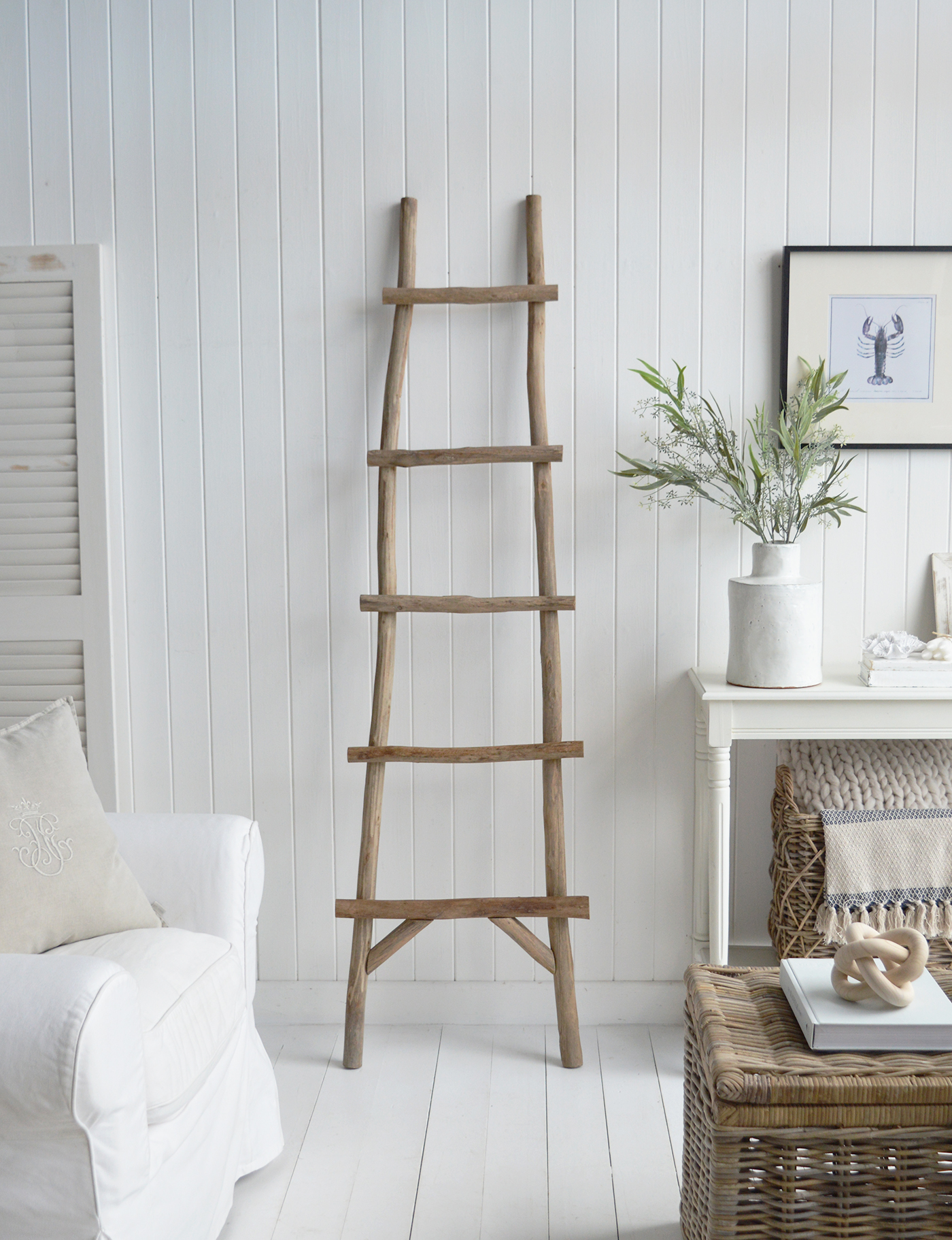 The Casco Bay trunk coffee table in a neutrally inspired living room alongside the driftwood ladder, for chic coastal style. Add a touch of rustic charm to your bedroom by using a driftwood blanket ladder to display cozy throws, linen blankets, or even string lights for a soft, ambient glow.